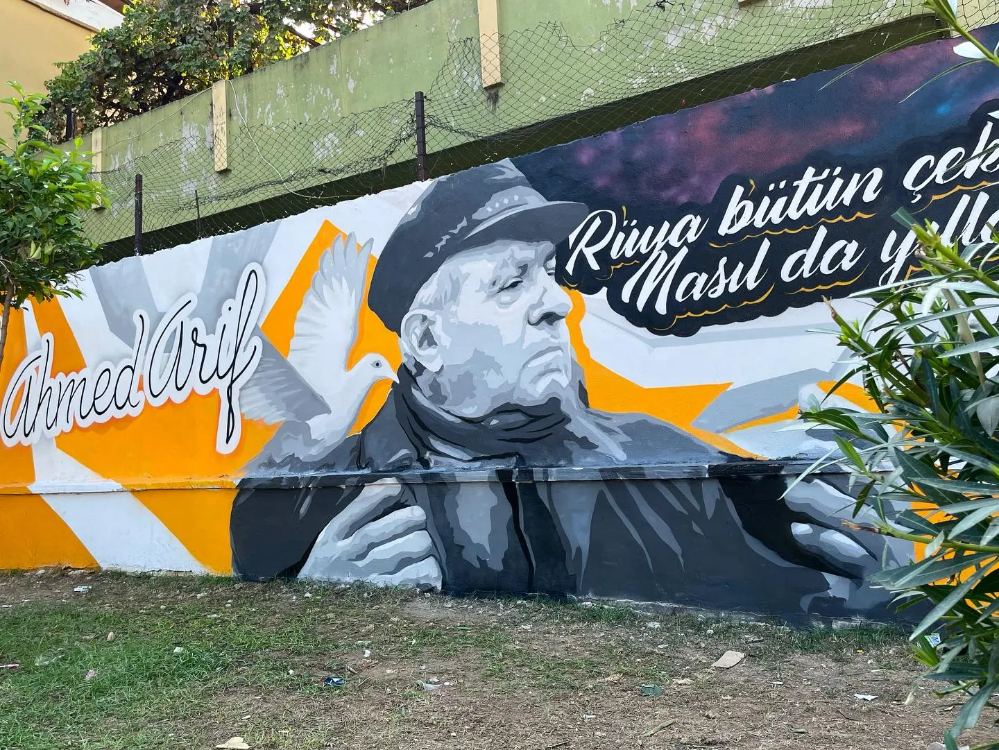 Ahmed Arif portresi ve sarı-beyaz bantlı dış duvar